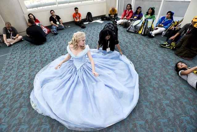 Carissa Ohm, dressed as Cinderella, takes a break as Annie Huynh adjusts her dress on the second day of the 2015 Comic-Con International held at the San Diego Convention Center Friday, July 10, 2015, in San Diego.  (Photo by Denis Poroy/Invision/AP Photo)