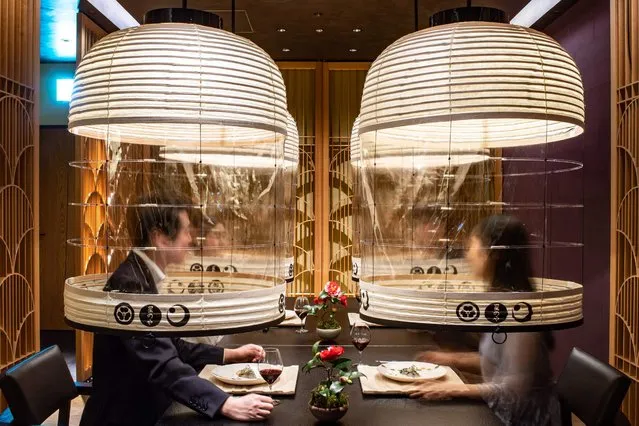 In this long exposure picture, staff members from the Hoshinoya Tokyo hotel demonstrate the “Lantern Dining Experience”, where lanterns made by Kojima Shoten – a shop in Kyoto – are used to shroud diners for mask-free dining amid the Covid-19 coronavirus pandemic, during a media event at the hotel in Tokyo on February 28, 2022. (Photo by Philip Fong/AFP Photo)