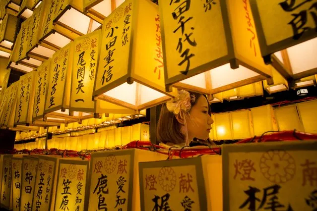 A woman stands between lanterns during the annual Mitama Festival at the Yasukuni Shrine in Tokyo, Japan, July 13, 2015. (Photo by Thomas Peter/Reuters)