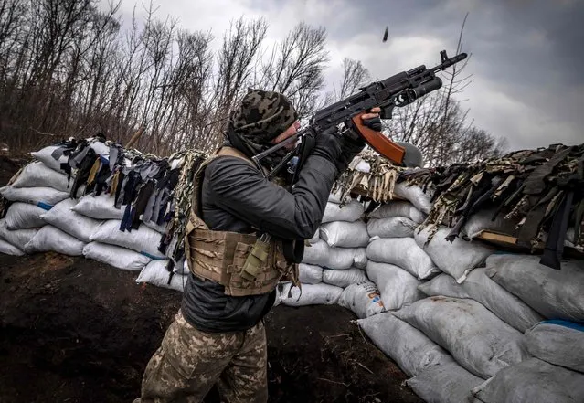 A Ukrainian serviceman shoots with an assault rifle from a trench at the front line east of Kharkiv on March 31, 2022. Russian forces are repositioning in Ukraine to strengthen their offensive on the Donbass, Nato said on March 31, 2022, on the 36th day of the Russian-Ukrainian conflict, as shelling continues in Kharkiv (north) and Mariupol (south). (Photo by Fadel Senna/AFP Photo)
