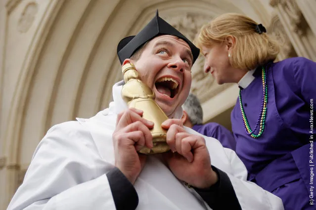 Father Matthew Hanisian, assistant rector at St. Alban's Parish, poses with his gold-painted syrup bottle trophy after winning a pancake race during the Shrove Tuesday, or Mardi Gras, tradition at the National Cathedral