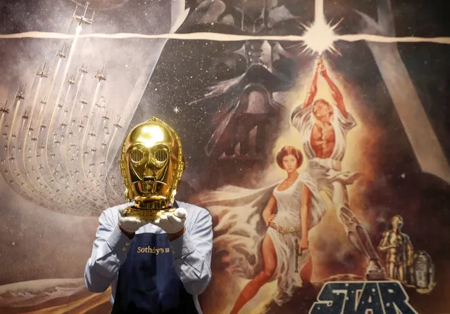 A Sotheby's employee poses with a “Return of the Jedi” promotional C-3PO Helmet 1983, estimated at £15,000-£25,000 created by George Lucas' visual effects company during a photocall at Sotheby's in London, Britain on December 6, 2019. (Photo by Thomas Mukoya/Reuters)