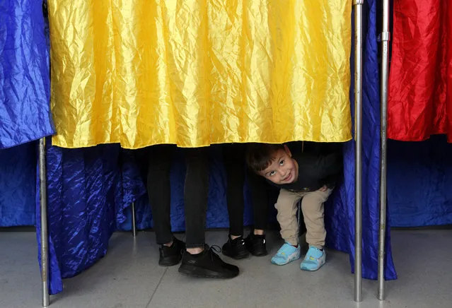 A Romanian kid stare out of the voting booth while waiting for his mother to stamp her ballot at 'Cezar Bolliac' polling station during the first round of presidential elections in Bucharest, Romania, 10 November 2019. Romanians are voting today for the first round of the presidential elections. (Photo by Robert Ghement/EPA/EFE)