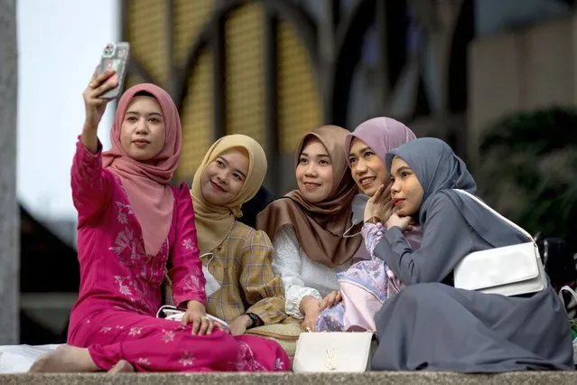 Young women take pictures following morning prayers at The Foundation of the Islamic Centre of Thailand mosque during Eid al-Fitr celebrations, marking the end of the Muslim holy month of Ramadan, in Bangkok on May 2, 2022. (Photo by Jack Taylor/AFP Photo)