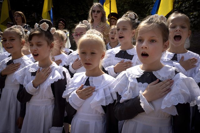 Schoolgirls sing the national anthem on the first day at school in a cadet lyceum in Kyiv, Ukraine, Monday, September 2, 2024. Children and students went to school despite the fact that Kyiv was hit by massive Russian missile barrage early in the morning, causing fires, damaged buildings and infrastructure objects. (Photo by Efrem Lukatsky/AP Photo)