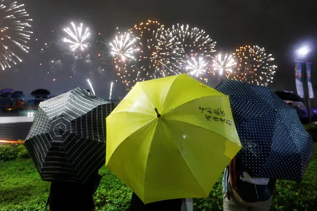 A pro-democracy protester holds a yellow umbrella, the symbol of the Occupy Central movement, as she watches fireworks explode over Victoria Harbour, as part of the celebration for the 20th anniversary of the city's handover from British to Chinese rule, in Hong Kong, China July 1, 2017. (Photo by Tyrone Siu/Reuters)