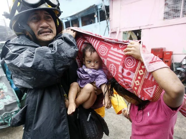 A Filipino rescue worker carries a child after an evacuation was implemented due to Typhoon Rammasun in Manila, Philippines, 16 July 2014. (Photo by Dennis M. Sabangan/EPA)