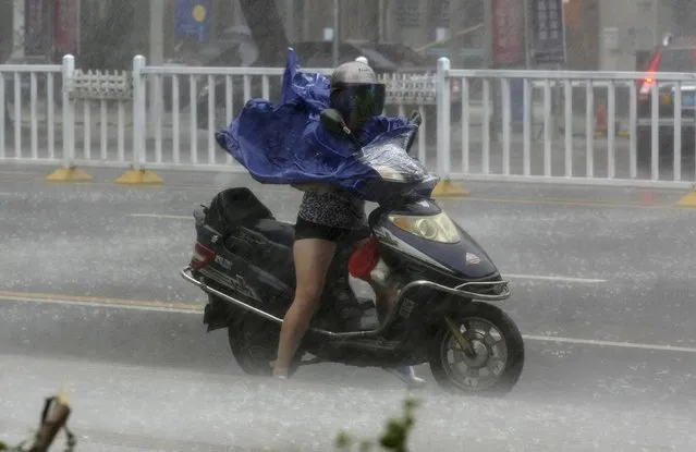 A woman rides her electric bicycle against the strong wind and heavy rainfall as Typhoon Rammasun hits Zhanjiang, Guangdong province July 18, 2014. A super typhoon slammed into China on Friday killing one person, as the government ordered an all-out effort to prevent loss of life from a storm that has already killed at least 64 people in the Philippines. Rammasun made landfall at Wenchang city on south China's island province of Hainan on Friday afternoon. (Photo by Reuters/Stringer)