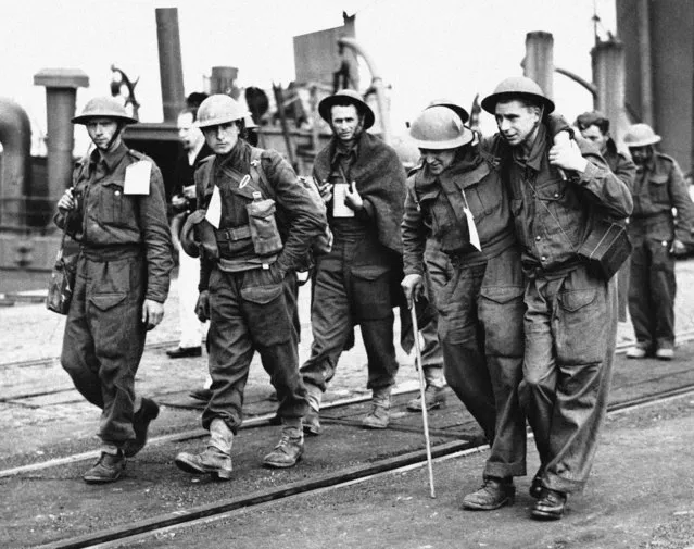 Men of the British Expeditionary Force arriving at a British port on June 6, 1940 after their escape from the German sweep through Flanders. One soldier assists a wounded comrade who walks with the aid of a stick. (Photo by AP Photo)