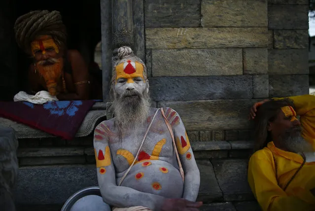 A group of Nepalese Sadhus (holy men) take rest as they wait for devotees receive the TIKA from them  during a Sarwan Brata (fast) festival at the Pashupati temple in Kathmandu, Nepal, 17 August 2015. Thousands of married and unmarried Nepalese Hindu women wearing red, yellow and green attires flocked to temples this month to pray for a long and prosperous life of their husbands or to find a good husbands. The fasting is undertaken every Monday exclusively by women by worshipping Lord Shiva. (Photo by Narendra Shrestha/EPA)