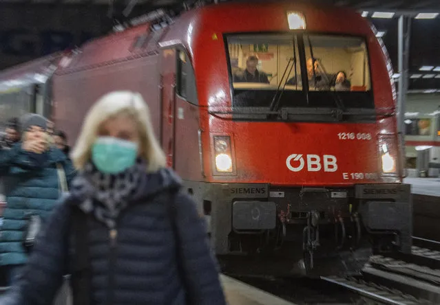 A woman wearing a breathing mask walks in front of the Eurocity train at the main station in Munich, Germany, Monday, February 24, 2020. The train was stopped at the Brenner Pass for several hours last night by authorities following fears that the had two people on board who may have been infected with the COVID-19 virus. (Photo by Lino Mirgeler/dpa via AP Photo)