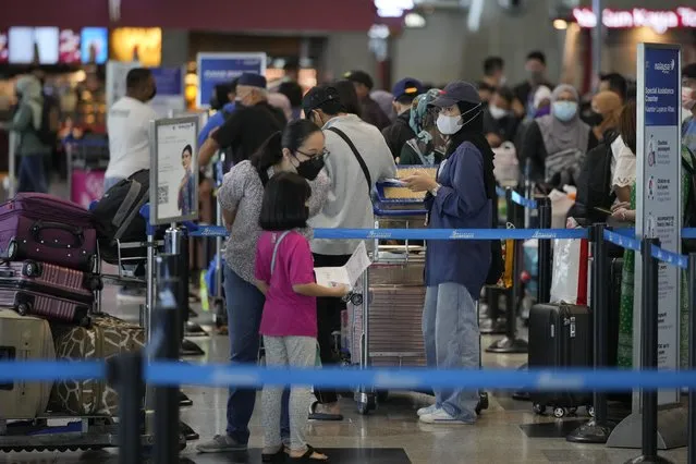 Travelers line up at check in counter at Kuala Lumpur International Airport in Sepang, Malaysia, Friday, April 1, 2022. Malaysia's international borders open to foreigners on Friday and fully vaccinated travelers do not have to undergo quarantine. (Photo by Vincent Thian/AP Photo)