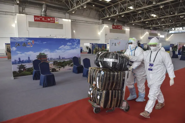 In this March 17, 2020 photo released by China's Xinhua News Agency, workers in protective suits push a cart with passengers' luggage at the New China International Exhibition Center, which has been converted into a facility to screen international flight passengers arriving in Beijing. As the pandemic expanded its reach, China and South Korea were trying to hold their hard-fought gains. China is quarantining new arrivals, who in recent days have accounted for an increasing number of cases, and South Korea starting Thursday will increase screenings of all overseas arrivals. The virus causes only mild or moderate symptoms, such as fever and cough, for most people, but severe illness is more likely in the elderly and people with existing health problems. (Photo by Peng Ziyang/Xinhua via AP Photo)