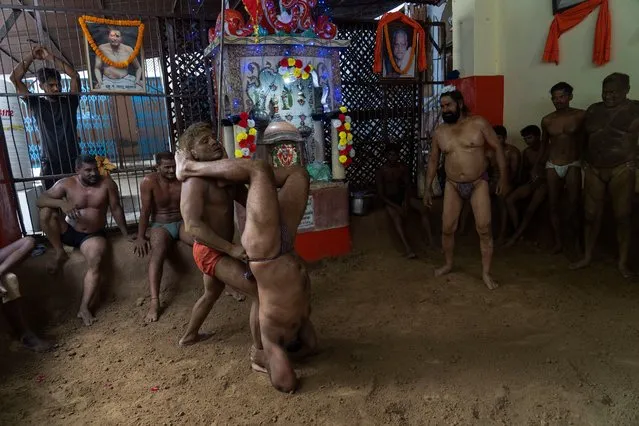 Traditional wrestlers engage in a bout of wrestling during Nag Panchami festival in Prayagraj, India. Tuesday, August 2, 2022. Every year, the wrestlers offer prayers and hold bouts to mark the festival which is primarily dedicated to the worship of snakes. (Photo by Rajesh Kumar Singh/AP Photo)