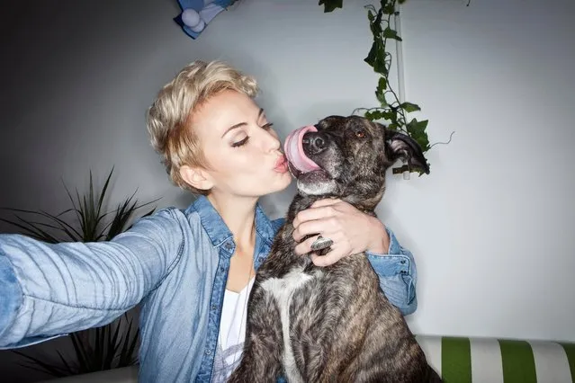 Smiling woman taking picture with dog. (Photo by Severin Schweiger/Getty Images)
