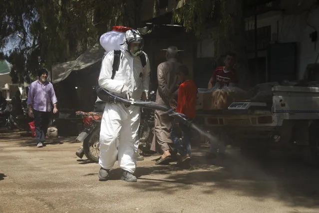 In this Tuesday, April 14, 2020 file photo, a member of a non-governmental aid organization spray disinfectant as a preventive measure for coronavirus in the town of Armnaz, Idlib province, Syria. Wealthier Western countries are considering how to ease lockdown restrictions and start taking gradual steps toward reviving business and daily life. But many developing countries, particularly in the Middle East and Africa, can hardly afford the luxury of any misstep. (Photo by Ghaith Alsayed/AP Photo/File)