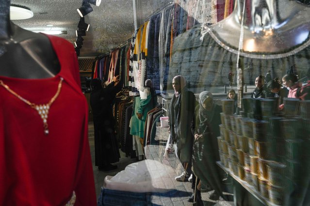Pedestrians are reflected in a storefront window as they walk near the Damascus Gate in Jerusalem's Old City, Tuesday, December 3, 2024. (Photo by Matias Delacroix/AP Photo)