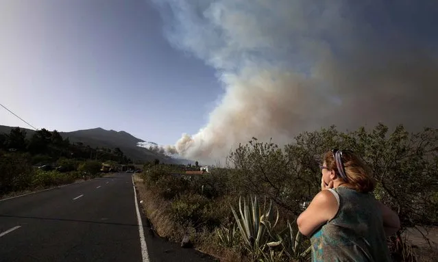 A woman watches as smoke rises from a wildfire raging on the outskirts of the town of El Paso on the Spanish canary island of La Palma on August 4, 2016. A forest officer died while fighting a fire and some 700 people were evacuated preventively in areas near the fire, which burned a thousand hectares in the mountains of Jedey overnight. (Photo by Desiree Martin/AFP Photo)