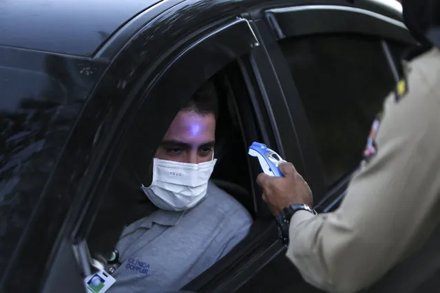 A member of the Municipal Civil Guard checks the temperature of a driver at a blockade on the border between the municipalities of Niteroi during the first lockdown day in the coronavirus (COVID-19) pandemic on May 11, 2020 in Niteroi, Brazil. The guards checks the temperature at people during a operation. According to the Brazilian Health Ministry, Brazil has 163,000 positive cases of coronavirus (COVID-19) and a total of 11,123 deaths. (Photo by Luis Alvarenga/Getty Images)