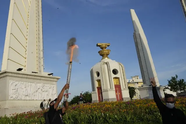 An anti-government protester shoots fire work into sky near Democracy Monument to demand that Prime Minister Prayuth Chan-ocha step down from his position in Bangkok, Thailand Tuesday, August 23, 2022. Thailand Constitutional Court on Monday received a petition from opposition lawmakers seeking a ruling on whether Prayuth has reached the legal limit on how long he can remain in office. (Photo by Sakchai Lalit/AP Photo)