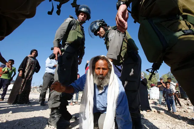 Palestinian Suleiman al-Hadhalin (C) is surrounded by Israeli border police as he tries to prevent Israeli authorities from destroying his house, that they said was built without permission, on August 9, 2016 in the village of Umm al-Kheir, south of the West Bank city of Hebron. (Photo by Hazem Bader/AFP Photo)