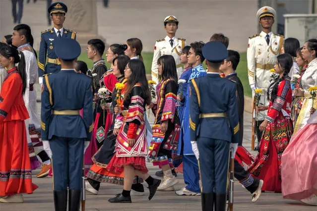 Participants in ethnic minority dress carry flowers as they walk during a ceremony to mark Martyr's Day at the Monument to the People's Heroes at Tiananmen Square in Beijing, Friday, September 30, 2022. (Photo by Mark Schiefelbein/AP Photo)