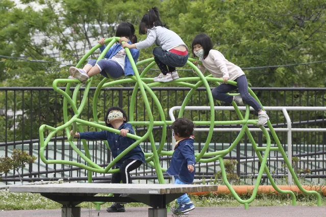 Children wearing face masks to protect against the spread of the new coronavirus play at a park in Yokohama, Kanagawa prefecture, near Tokyo, Wednesday, May 20, 2020. Kanagawa is still under a coronavirus state of emergency until the end of May, though there have been no hard lockdowns. (Photo by Koji Sasahara/AP Photo)