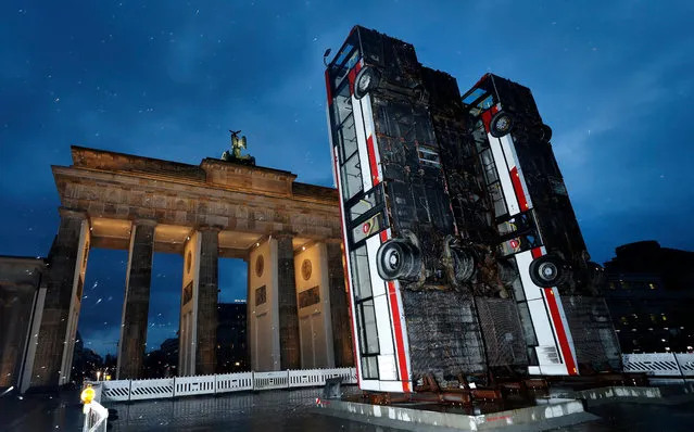 General view of the installation of the artwork “Monument”, created with three buses propped up vertically by Syrian-German artist Manaf Halbouni in front of the landmark Brandenburg Gate in Berlin, Germany, 10 November 2017. The artwork reminds of barriers made of buses in the streets of Aleppo, Syria that were erected to protect people from sniper fire. The installation is part of the “Herbstsalon” event taking place in Berlin in November 2017. (Photo by  Felipe Trueba/EPA/EFE)