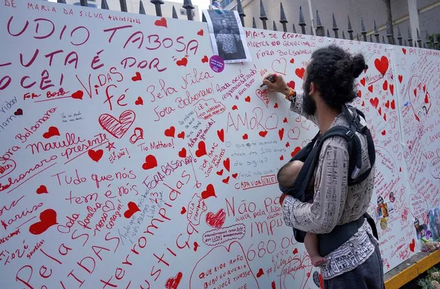 A man writes on a memorial wall as he takes part in a memorial ceremony in honour of the victims of the coronavirus disease (COVID-19) at Paulista Avenue in Sao Paulo, Brazil on October 23, 2022. (Photo by Mariana Greif/Reuters)