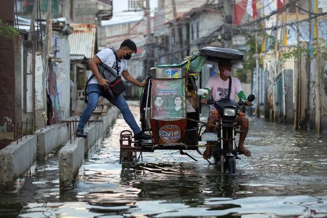 A man steps in a motorcycle taxi, modified to cope with flooding, in the coastal town of Hagonoy, Bulacan province, Philippines on September 23, 2022. (Photo by Eloisa Lopez/Reuters)