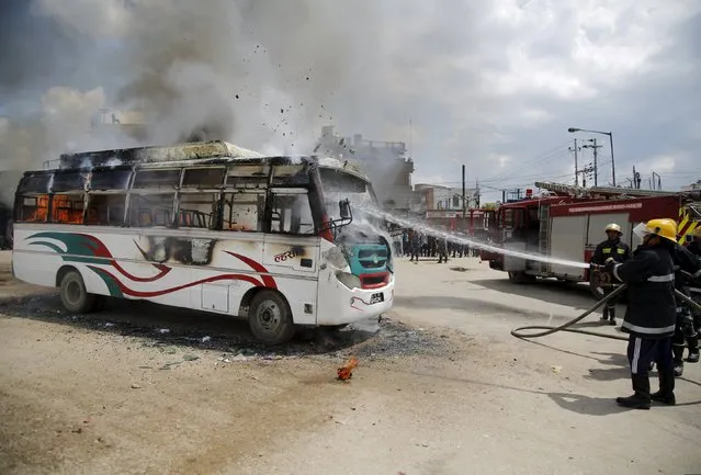 Firefighters try to douse fire set by unidentified protesters on a passenger bus during the nationwide strike, called by the opposition parties against the proposed constitution, in Kathmandu, Nepal September 20, 2015. (Photo by Navesh Chitrakar/Reuters)