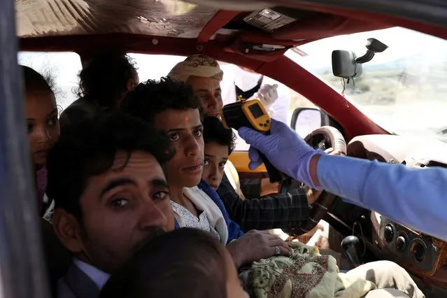 A health worker takes the temperature of people riding a taxi van, amid concerns of the spread of the coronavirus disease (COVID-19), at the main entrance of Sanaa, Yemen on May 9, 2020. (Photo by Khaled Abdullah/Reuters)