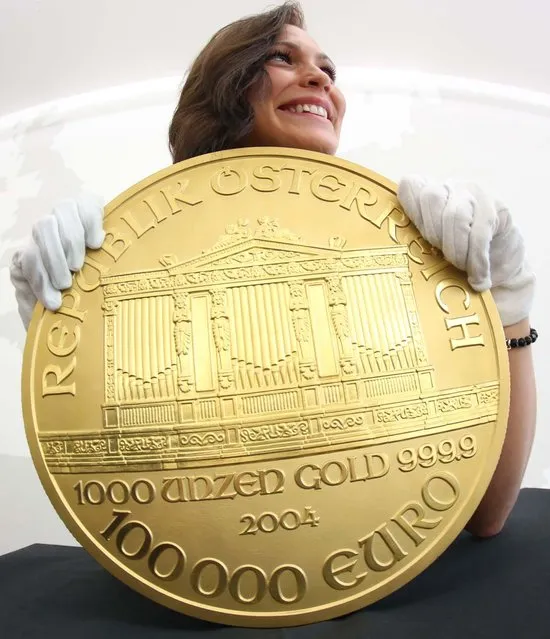 A woman presents Europe's biggest gold coin during an exhibition at the Pro Aurum trade house in Hamburg, northern Germany. The so-called “Big Phil” made after the model of an Austrian coin weighs around 31 kilograms and is worth more than 1.3 million euros or 1.7 million US dollars. “Big Phil” is on display at Pro Aurum until November 17, 2012. (Photo by Christian Charisius)