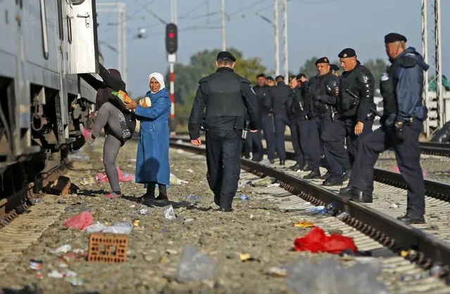 Migrants board a train as Croatian policemen line up at the railway station in Tovarnik, Croatia September 21, 2015. (Photo by Antonio Bronic/Reuters)