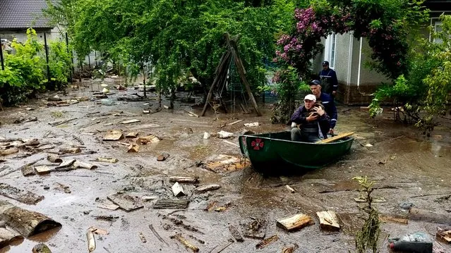 Rescuers evacuate a local resident and his dog from a flooded area in Chernivtsi region, Ukraine, in this handout picture released by Ukrainian State Emergency Service on June 25, 2020. (Photo by State Emergency Service of Ukraine in Chernivtsi region/Handout via Reuters)