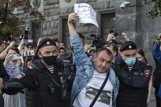 Police officers detain a protester as he comes to support Russian opposition leader Alexei Navalny in front of the building of the Federal Security Service (FSB, Soviet KGB successor) in Moscow, Russia, Thursday, August 20, 2020. The banner reads: “Navalny live!!! Politkovskaya? Nemtsov? Who is next? Putin is a thief”. (Photo by Pavel Golovkin/AP Photo)