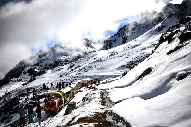 This photograph taken on February 19, 2024, shows visitors enjoy the view on a mountain train through the Artouste ski resort, where ski lifts do not operate due to a significant lack of snow, at Laruns, in the Pyrenees Atlantiques, south-western France, on the day of its reopening at the start of the local school holidays. It hasn't happened for over thirty years: at Artouste, a ski resort in the Pyrenees-Atlantiques, in the Ossau valley, the month of February without snow is a full-scale test for the resort, which is transforming its business to adapt to climate change. (Photo by Christophe Archambault/AFP Photo)
