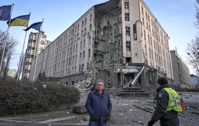 People stand in front of damaged hotel at the scene of Russian shelling in Kyiv, Ukraine, Saturday, December 31, 2022. (Photo by Efrem Lukatsky/AP Photo)