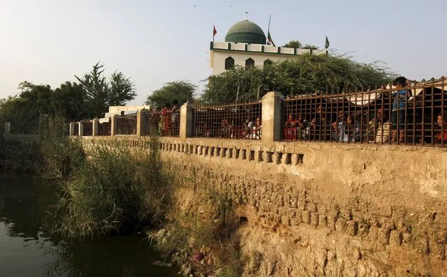 People look through a fence at the shrine of Hasan-al-Maroof Sultan Manghopir, better known as the crocodile shrine, on the outskirts of Karachi, Pakistan October 11, 2015. (Photo by Akhtar Soomro/Reuters)