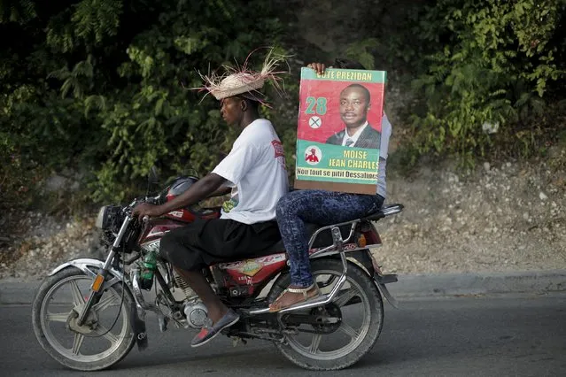 A woman holds a poster of presidential candidate Moise Jean Charles of Pitit Desalin political platform as she rides a bike during a rally in Port-au-Prince, Haiti, October 17, 2015. Haiti will hold presidential elections on October 25. (Photo by Andres Martinez Casares/Reuters)