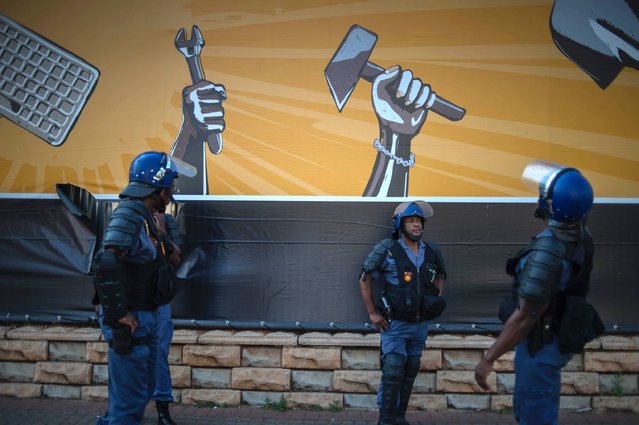 South African police officers stand by as University of Witwatersrand students march to the Confederation of South African Trade Unions (COSATU) headquarters in Johannesburg on September 23, 2016 during a protest to demand free higher education. The South African government vowed on September 22 to end violent student protests against higher tuition fees, after days of clashes on campuses and disrupted classes across the country. (Photo by Mujahid Safodien/AFP Photo)