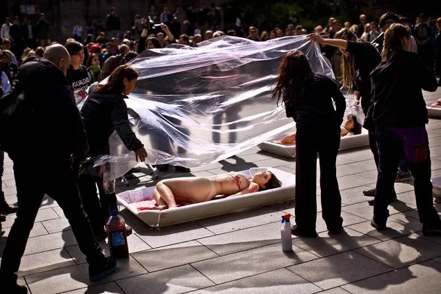 Animal rights activists from the group “Animal Equality” are covered with plastic sheets to represent meat packaging as they stage a protest during “Day Without Meat” event in Barcelona, Spain, on March 20, 2013. (Photo by Emilio Morenatti/Associated Press)