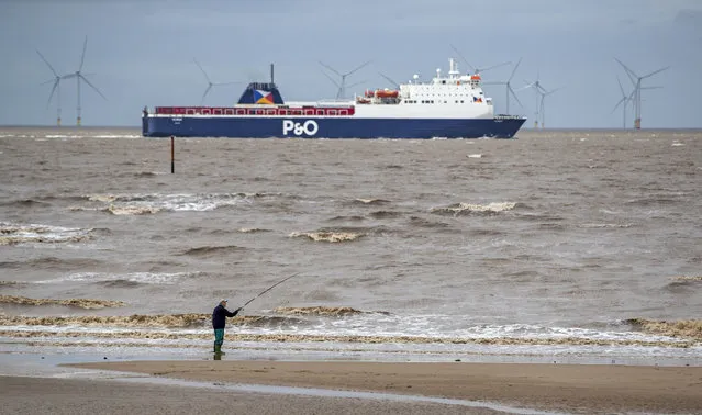 A passenger ferry heads down the River Mersey as a fisherman works on the beach at Crosby, England, Thursday September 3, 2020. (Photo by Peter Byrne/PA Wire Press Association via AP Photo)