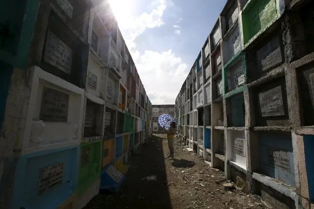 A woman offers prayers in front of the tomb of her departed relative buried in an "apartment-style" grave inside a cemetery in Navotas city, north of Manila October 31, 2015. (Photo by Romeo Ranoco/Reuters)