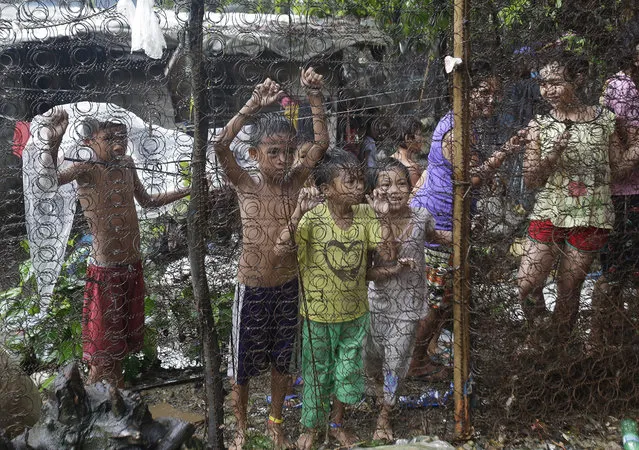 Filipino children watch as arrested drug suspects, not shown, wait outside an alleged drug den following a raid where two suspects were killed and about 90 people arrested during operations as part of the continuing “War on Drugs” campaign of Philippine President Rodrigo Duterte near the Payatas dumpsite in suburban Quezon city, north of Manila, Philippines,Wednesday, October 5, 2016. Duterte has told U.S. President Barack Obama “you can go to hell” in a recent speech that was his strongest tirade so far against the U.S. over its criticism of his deadly anti-drug campaign, adding that he may eventually decide to “break up with America”. (Photo by Aaron Favila/AP Photo)