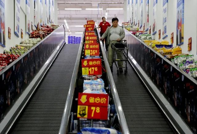 Shoppers ride on a travelator at a supermarket in Beijing, China, October 15, 2015. China's economic planner said on Thursday that consumer prices will continue to grow at a mild pace in coming months, amid investors' concerns about deflationary pressures in the economy. (Photo by Kim Kyung-Hoon/Reuters)