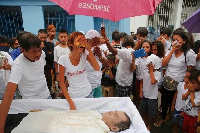 Diane Agregado, the daughter, and other relatives of Reynaldo Agregado, who was killed in a police anti-drugs operation, mourn over his body during the funeral in Manila, Philippines October 15, 2016. (Photo by Damir Sagolj/Reuters)