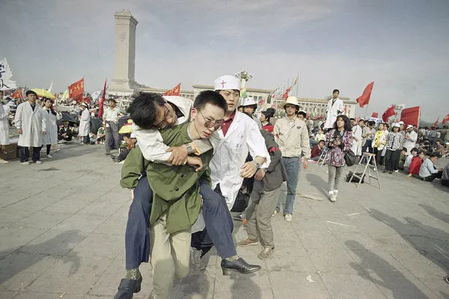 In this May 16, 1989 file photo, medics rush a Beijing university student from Tiananmen Square after he collapsed on the third day of a hunger strike in Beijing. A quarter century after the Communist Party's attack on demonstrations centered on Tiananmen Square on June 4, 1989, the ruling party prohibits public discussion and 1989 is banned from textbooks and Chinese websites. (Photo by Sadayuki Mikami/AP Photo)