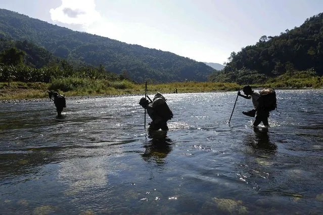 Naga men walk through a creek during a hunting trip between Donhe and Lahe township in the Naga Self-Administered Zone in northwest Myanmar December 28, 2014. The Naga in this area are mainly Christian and regular hunting parties comprise three to 10 people. (Photo by Soe Zeya Tun/Reuters)
