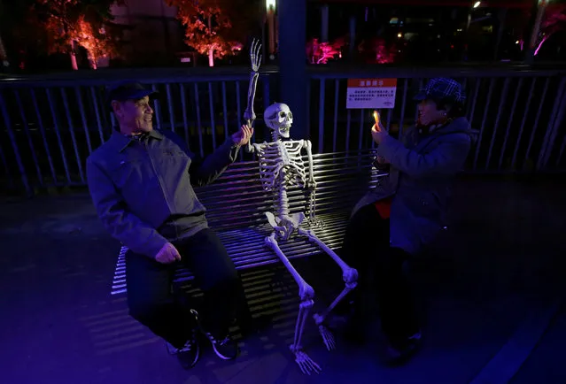 A woman takes a photo of a fake skeleton ahead of a Halloween parade at Happy Valley park in Beijing, China October 31, 2016. (Photo by Jason Lee/Reuters)